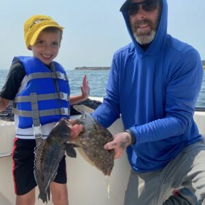 photo of a young boy and his father caught a seabass and a fluke