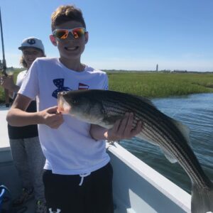 2 boys caught a striped bass on the bay at summer camp