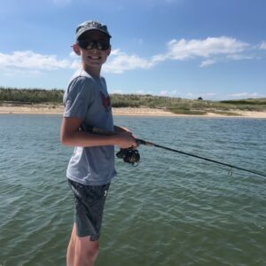 a boy fishing at summer camp with Bay Camp Charters on the water